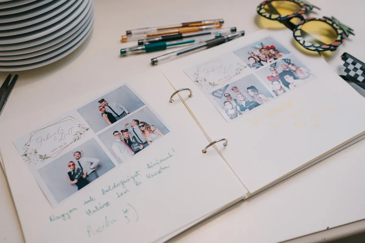 Pagini deschise de guestbook cu fotografii din cabina foto și mesaje scrise de invitați